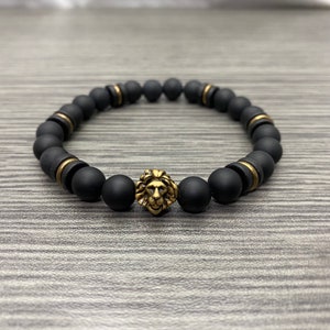 May include: Black beaded bracelet with a gold lion head charm.