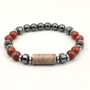 May include: A bracelet with brown wooden beads, black hematite beads, and a light brown stone bead in the center.