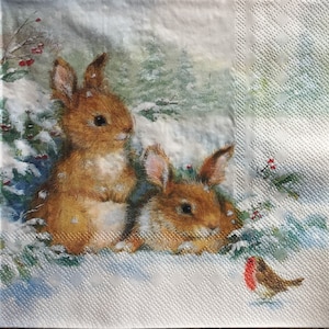 May include: Two brown rabbits with long ears are sitting in the snow. The rabbits are looking to the right of the image. A small red robin bird is perched on a branch in the lower right corner of the image.