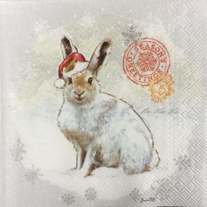 May include: A square paper napkin featuring a brown and white rabbit wearing a red Santa hat with green holly. The design includes a red circular stamp with the text Season's Greetings, a snowflake motif, and the handwritten text Ho Ho Ho.