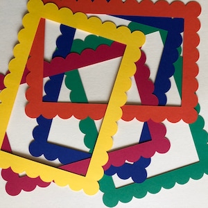 Può includere: Cinque cornici di carta festonate in diversi colori: giallo, rosso, blu, verde e rosso scuro. Le cornici sono sovrapposte, creando un design colorato e astratto.