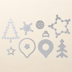 May include: A set of ten silver metal Christmas-themed die-cut shapes. The shapes include a snowflake, a star, a tree, a bell, and a circle.