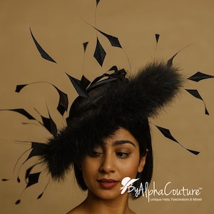 Puede incluir: Un fascinador negro con base de malla, adornado con plumas negras y detalles en forma de diamante. El tocado presenta un adorno de plumas esponjosas, ideal para eventos especiales.