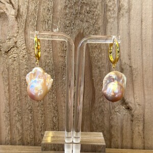 May include: A pair of gold hoop earrings with large, irregular, iridescent pearl drops.