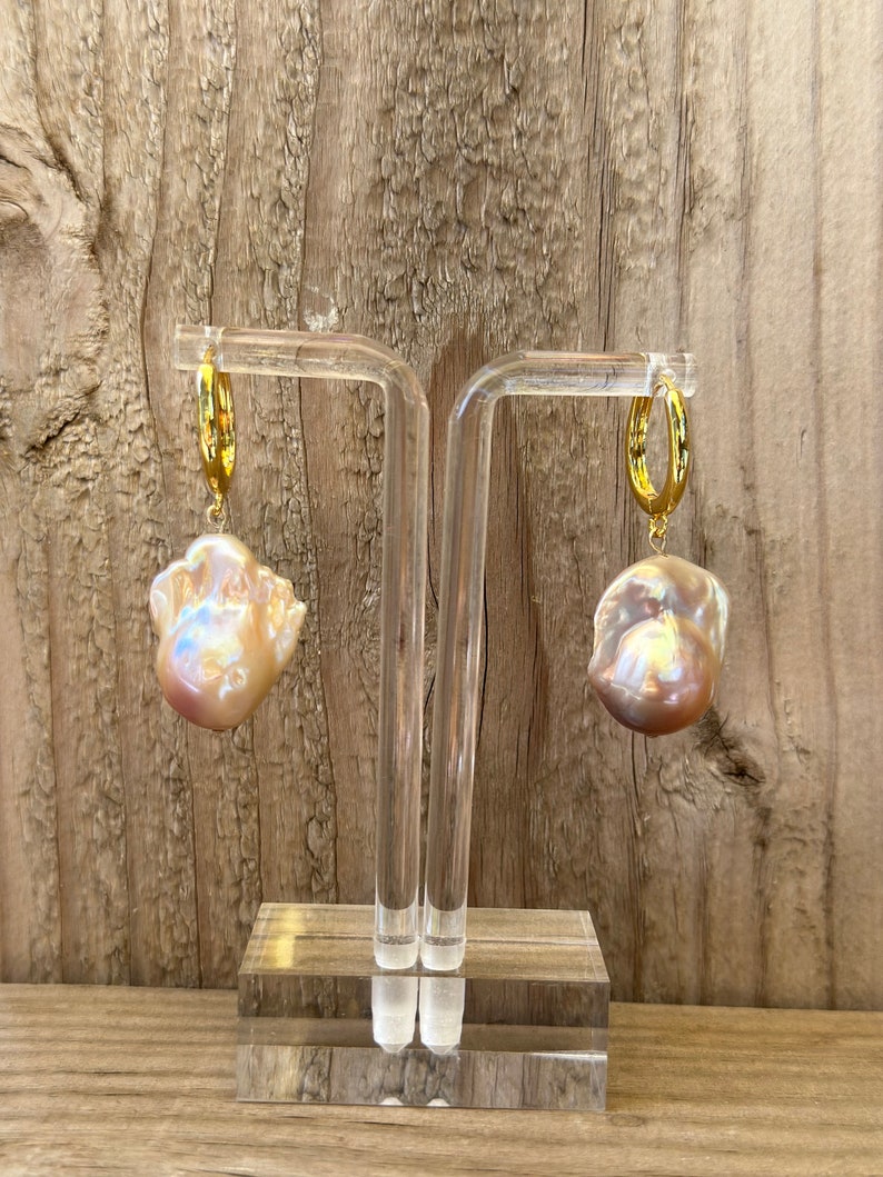 May include: A pair of gold hoop earrings with large, irregular, iridescent pearl drops.
