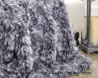 May include: A soft, grey and white faux fur throw blanket draped over a chair. The blanket has a long, shaggy pile and is perfect for adding warmth and texture to any room.