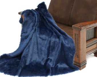 May include: A plush navy blue faux fur throw blanket draped over a brown leather couch. The blanket is soft and fluffy, perfect for adding warmth and comfort to any room.