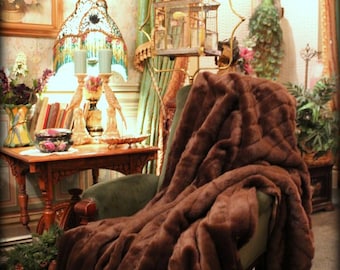 May include: A brown faux fur throw draped over a plush armchair in a vintage living room setting. The throw is soft and luxurious, with a subtle sheen. The text "Fur Accents Plush Pelt Throws" is displayed below the throw.