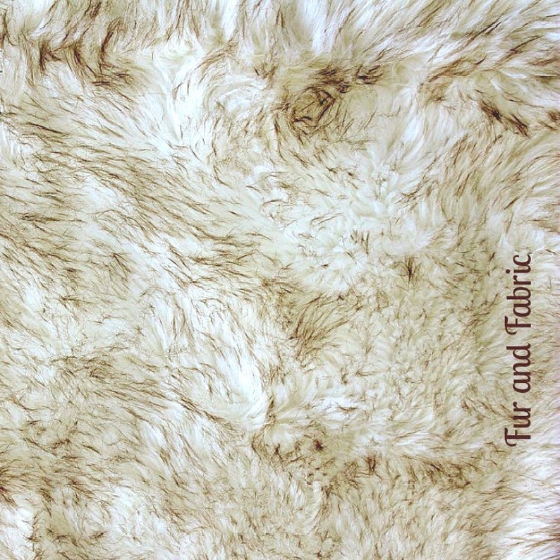 Pu&ograve; includere: Primo piano di un tessuto in pelliccia sintetica bianco e marrone. Il tessuto ha una texture morbida e soffice ed &egrave; perfetto per progetti di artigianato.