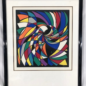 May include: Abstract art print in a black frame. The artwork features a colorful, swirling design with shapes in red, blue, yellow, green, purple, and white against a black background. The frame is black with a white mat.