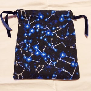 May include: A black drawstring bag with a constellation pattern in blue and white. The bag has blue ribbon ties.