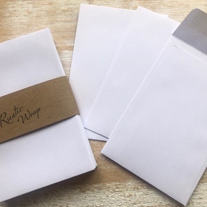 Op de afbeelding: Een stapel witte blanco kaartjes met een bruin papieren bandje waarop "Rustic Wrap" staat.
