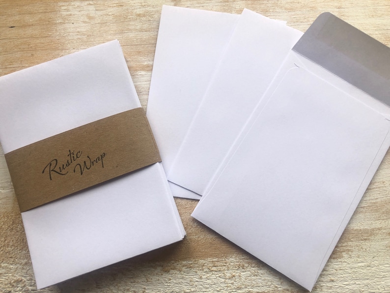 Op de afbeelding: Een stapel witte blanco kaartjes met een bruin papieren bandje waarop "Rustic Wrap" staat.