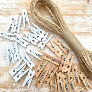 May include: A collection of wooden pegs, some painted white and some natural wood, with a roll of twine.