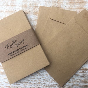 Op de afbeelding: Een stapel bruine mini manila enveloppen gemaakt van 100% gerecycled papier. De enveloppen zijn verpakt met een bruin bandje waarop "Rustic Wrap" en "Mini Manila Envelopes" staat.
