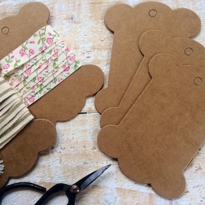 May include: Several brown paper thread spools with a decorative edge, alongside fabric ribbon samples. One ribbon features a floral print, and another has a striped pattern. A pair of black scissors and a daisy are also visible.