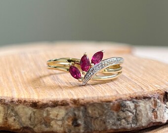 Gold ruby ring. A petite 9K yellow gold ring, with a trilogy of marquis cut natural rubies and pavé set diamonds in a turned setting.