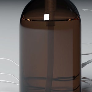 Peut inclure: Une bouteille en verre brun foncé avec un distributeur à pompe noir. La bouteille est remplie d'un liquide clair.