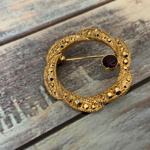 Gold circle brooch with garnet stone