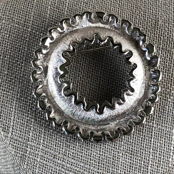 Ruffled silver tone tradition circle brooch with textured brushed metal design from the 1960s