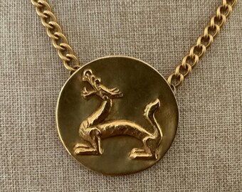 Réplicas del Museo Alva: Collar con medallón de dragón en tono dorado y colgante de bestia mítica.