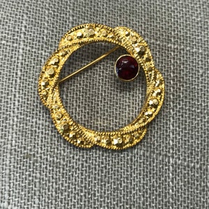 Gold circle brooch with garnet stone