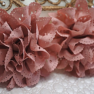 May include: Two dusty rose fabric flowers with a scalloped edge and a dotted pattern.