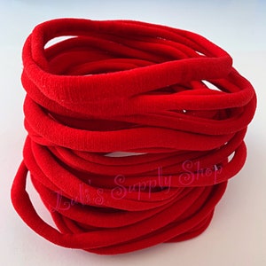 May include: A stack of red hair ties, made of soft, stretchy fabric. The hair ties are arranged in a spiral pattern.