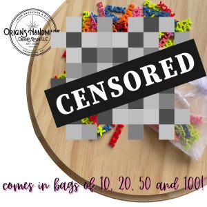 May include: A wooden serving board with colorful word charms, partially obscured by a "CENSORED" banner. The charms are in various colors and spell out words. The text "comes in bags of 10, 20, 50 and 100!" is also visible.