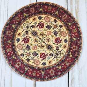May include: Round, cream-colored coaster with a red, black, and gold intricate floral pattern.