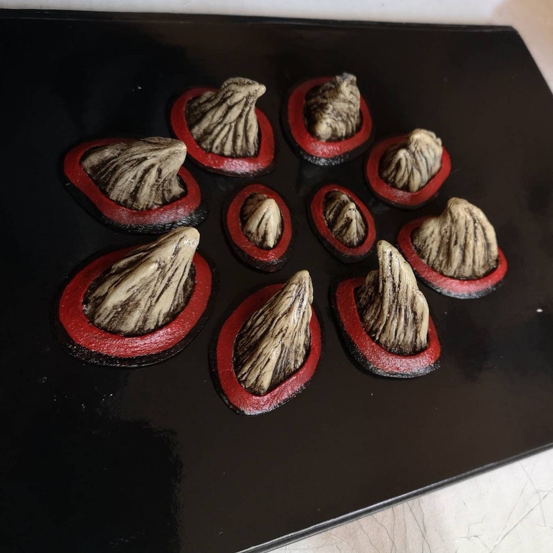 May include: A black background with ten beige, textured, 3D spikes with red rings around each one. The spikes are arranged in a circular pattern.