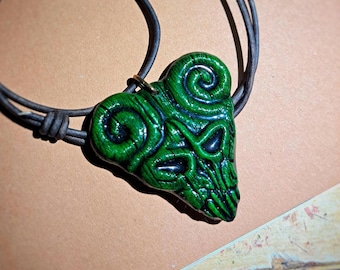 May include: A green pendant necklace with a heart-shaped design. The pendant features a detailed, textured pattern with dark green and black accents. The necklace has a black cord.