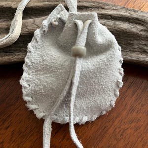 Pochette amérindienne - sac cousu main / sac de cou - en peau de cerf de couleur grise, décorée d'une perle de corbeau grise