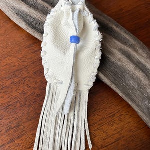 Pochette amérindienne - sac cousu main / sac de cou - en peau de cerf de couleur blanche, décorée d'une perle de corbeau bleu et de franges