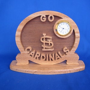 May include: A wooden clock with a St. Louis Cardinals logo and the words "GO CARDINALS". The clock has a gold-colored face and hands.