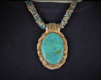 May include: A turquoise gemstone pendant necklace with a gold-toned metal frame and a beaded chain.