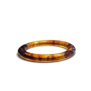May include: A circular bangle bracelet featuring a translucent amber and dark brown tortoiseshell pattern. The accessory has a smooth, polished finish and a rounded profile, showcasing a classic marbled aesthetic with varying tones of golden brown and deep espresso.