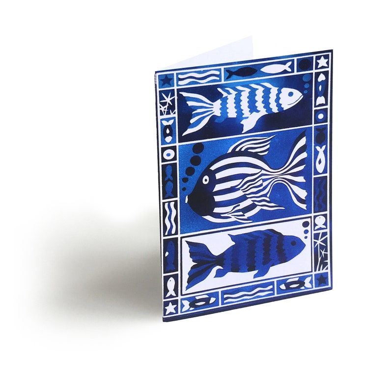 May include: A blue and white greeting card with a stylized design of three fish. The fish are outlined in white and have a blue and white striped pattern. The card has a white background and a blue border.