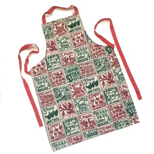May include: A red and white Christmas-themed apron with a green and red print of the 12 Days of Christmas song lyrics. The apron has adjustable straps and a large pocket.