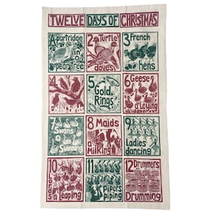 May include: A white kitchen towel with a green and red illustration of the Twelve Days of Christmas. The illustration features a different image for each day, such as a partridge in a pear tree, two turtle doves, three French hens, and so on.