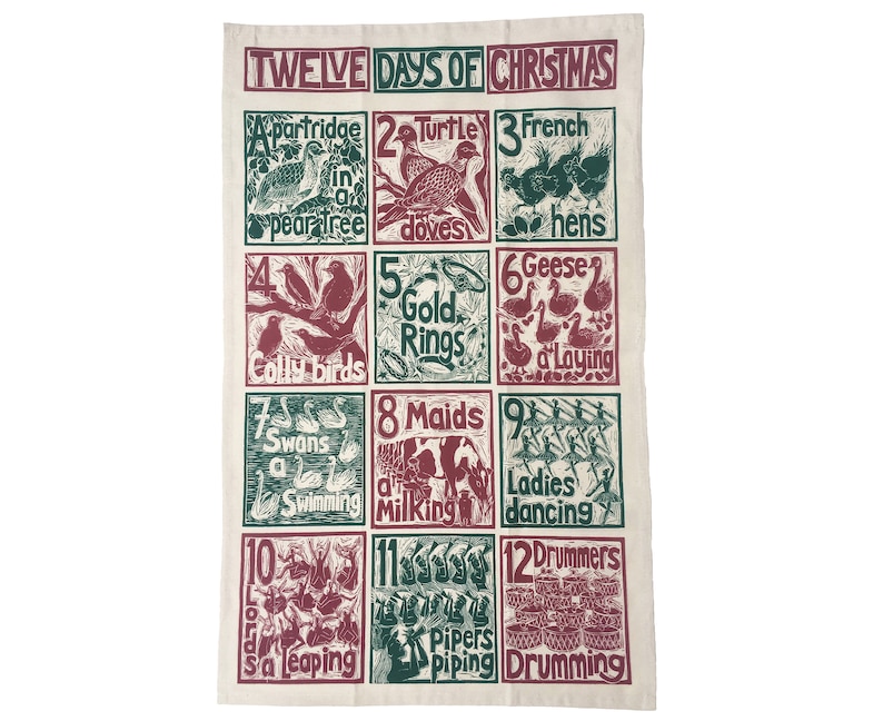 May include: A white kitchen towel with a green and red illustration of the Twelve Days of Christmas. The illustration features a different image for each day, such as a partridge in a pear tree, two turtle doves, three French hens, and so on.