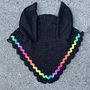 May include: Black horse fly bonnet with rainbow trim. The bonnet has ear covers and a scalloped edge.
