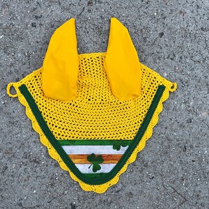 May include: Yellow crochet horse fly mask with green trim and a shamrock design. The mask has two yellow ear covers.