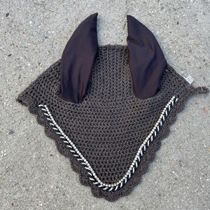 May include: A brown crocheted horse fly bonnet with black ear covers and a silver chain trim.