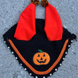 May include: Black horse fly bonnet with orange trim and a pumpkin patch design. The bonnet has two red ear covers with black and orange pom-poms.