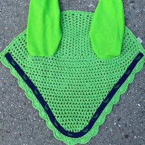 May include: A bright green horse fly bonnet with navy blue trim and green whale designs. The bonnet has two ear covers that are also bright green.