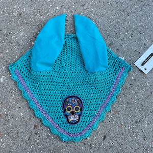 May include: A turquoise crochet horse fly bonnet with purple trim and a sugar skull design.