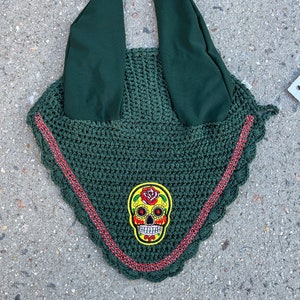 May include: Green crochet horse fly bonnet with red trim and a colorful sugar skull design.