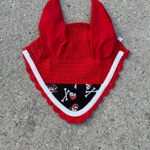 May include: Red crochet horse fly bonnet with white trim and a black skull and crossbones print.