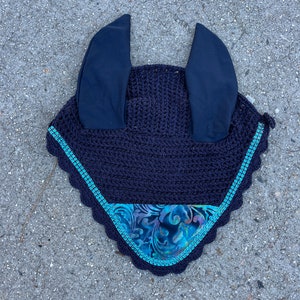 May include: A navy blue fly bonnet with a teal and black patterned trim and ear covers.